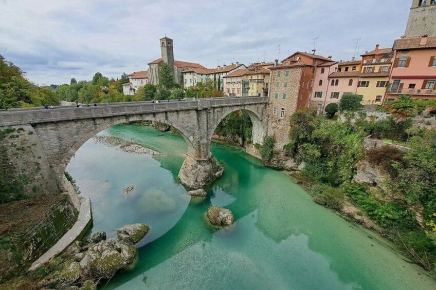 A stone bridge over a river with a tower, surrounded by buildings. 3
