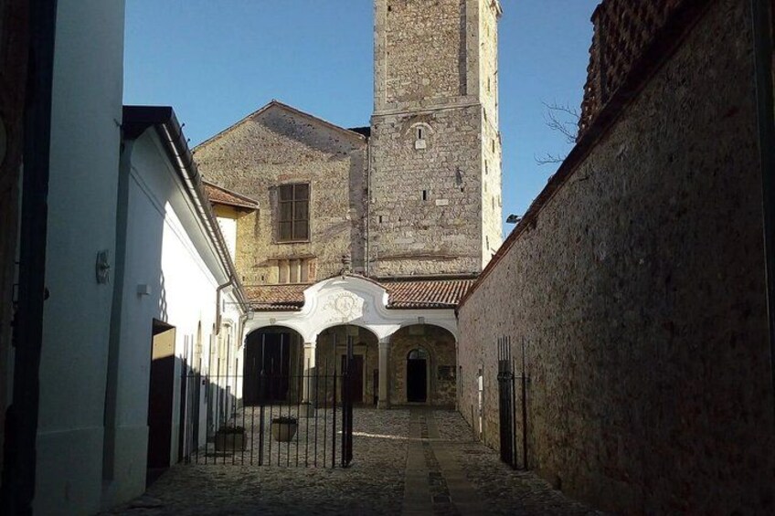 A cobblestone alleyway leading to a historic building with a tall tower. 2