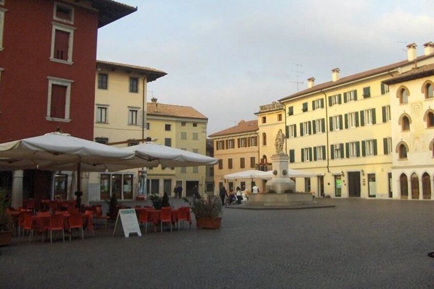 A plaza with outdoor seating, a fountain, and historic buildings. 4