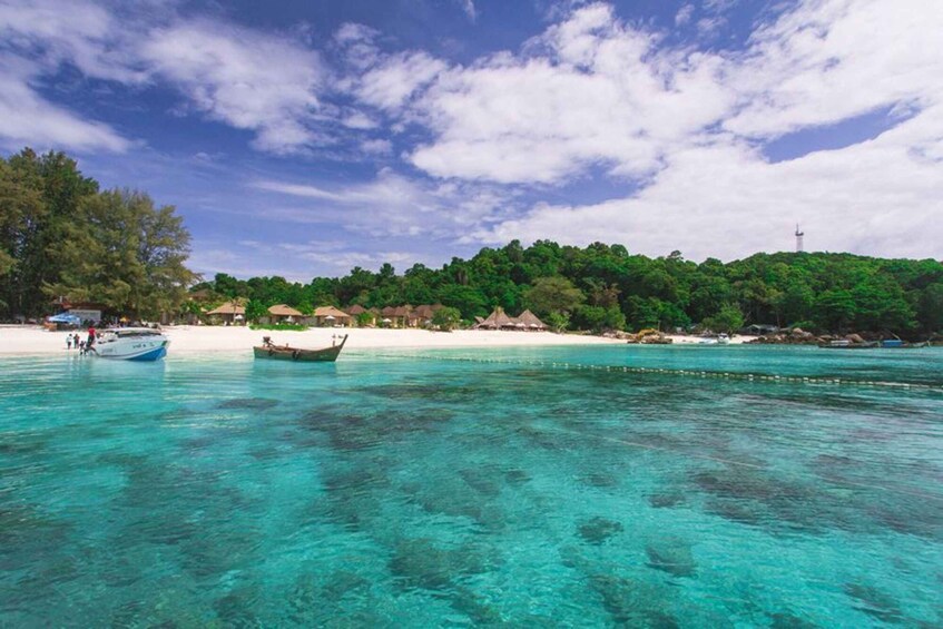 A tropical beach with clear turquoise waters, a boat, and a lush green hill in the background. 2