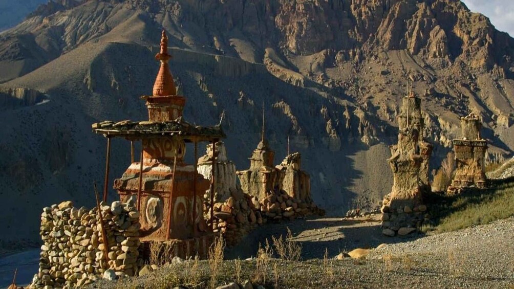 A traditional Tibetan prayer wheel and stupa set against a mountainous backdrop. 3