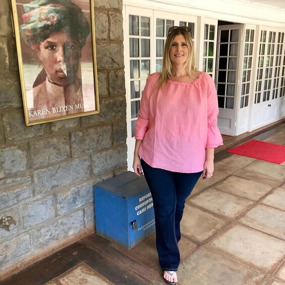 A person standing in a building with a framed artwork on the wall and a blue box on the floor. 3