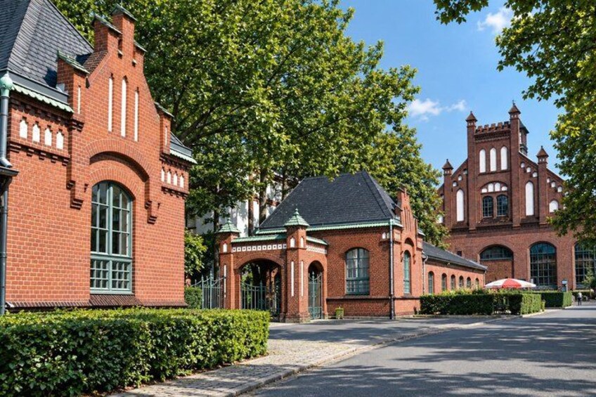 A red brick building with a green roof, surrounded by lush green trees and a clear blue sky. 3
