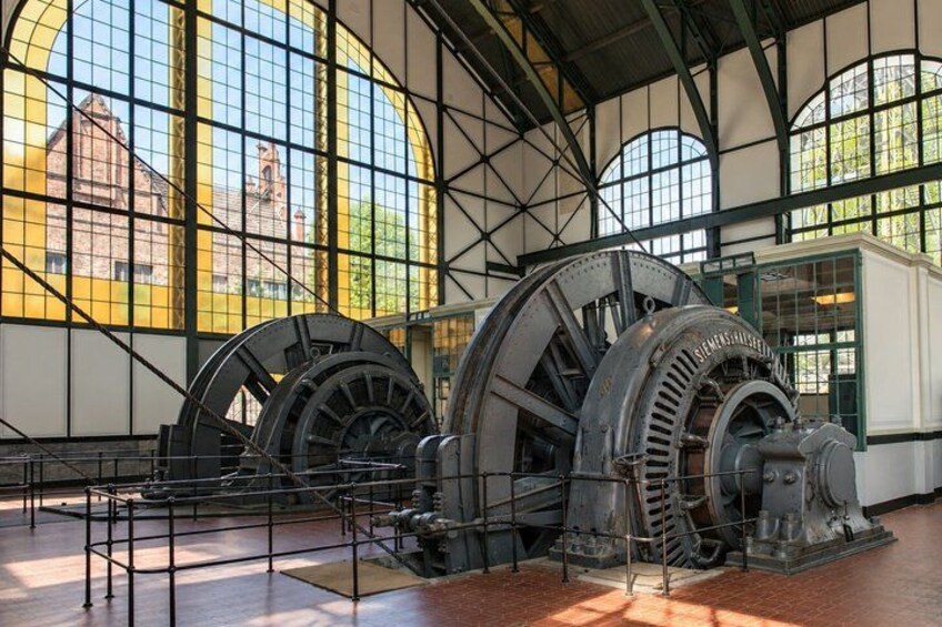 Large industrial water wheels inside a building with large windows. 2