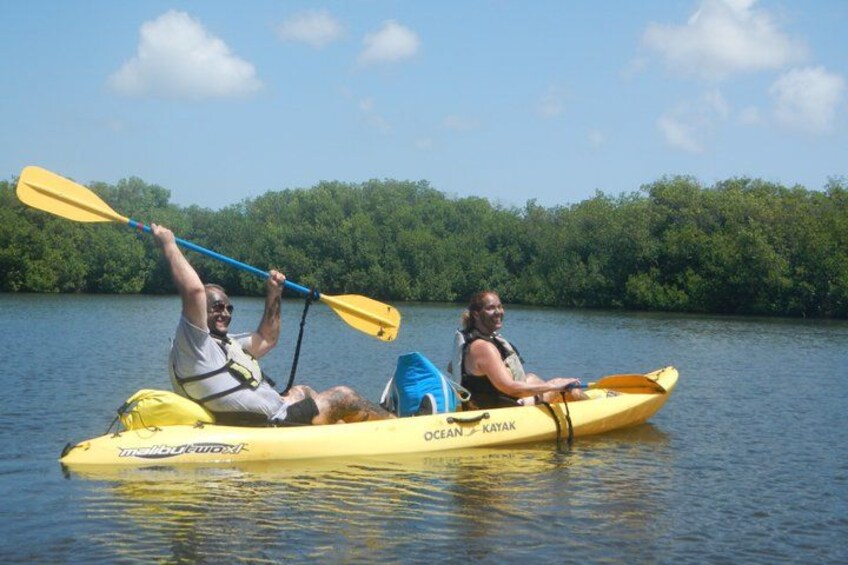 Two people kayaking on a calm lake surrounded by dense greenery. 3