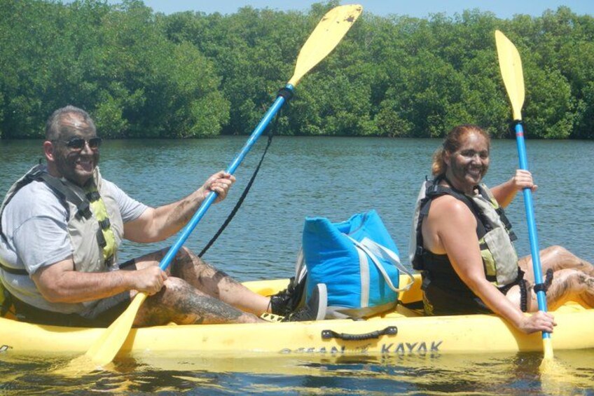 Two people kayaking on a river with a forested background. 2