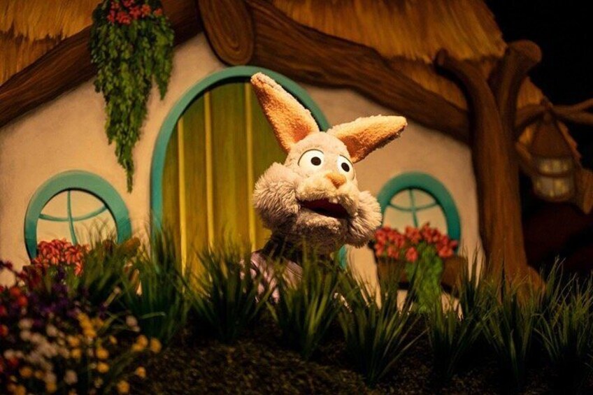 A rabbit figurine in front of a house with a green door and a thatched roof. 3