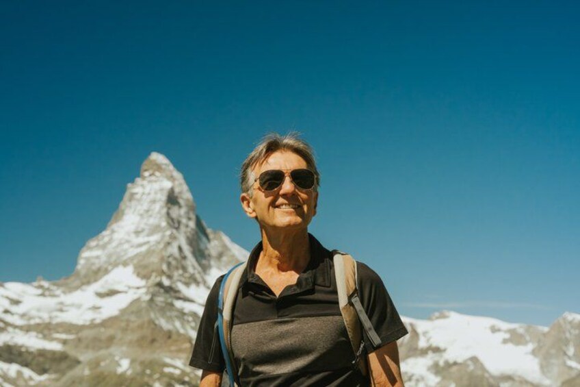 A person standing on a mountain with a clear sky and a prominent peak in the background. 3