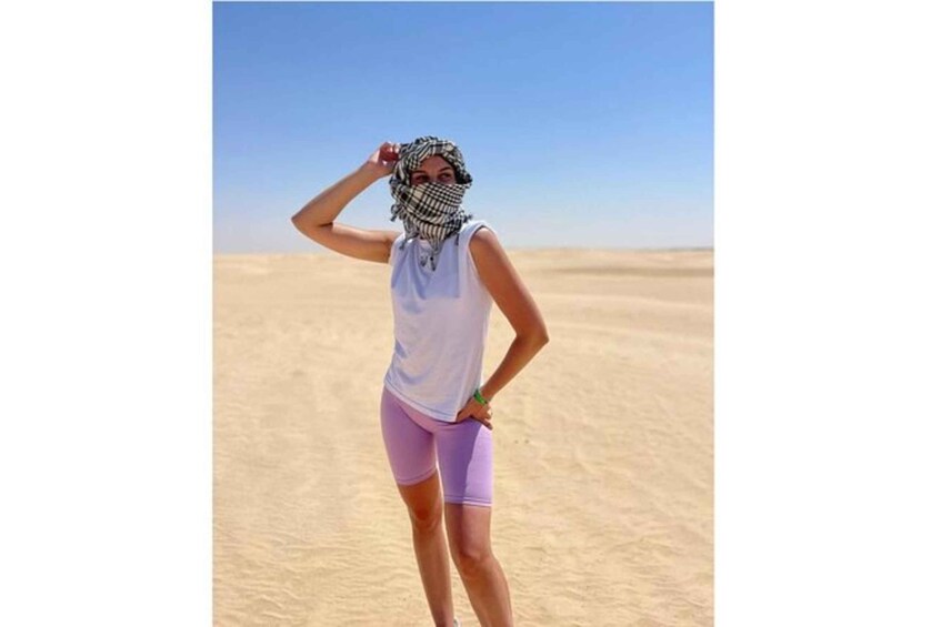 Une personne se tient debout dans un désert, avec des dunes de sable en arrière-plan. 3