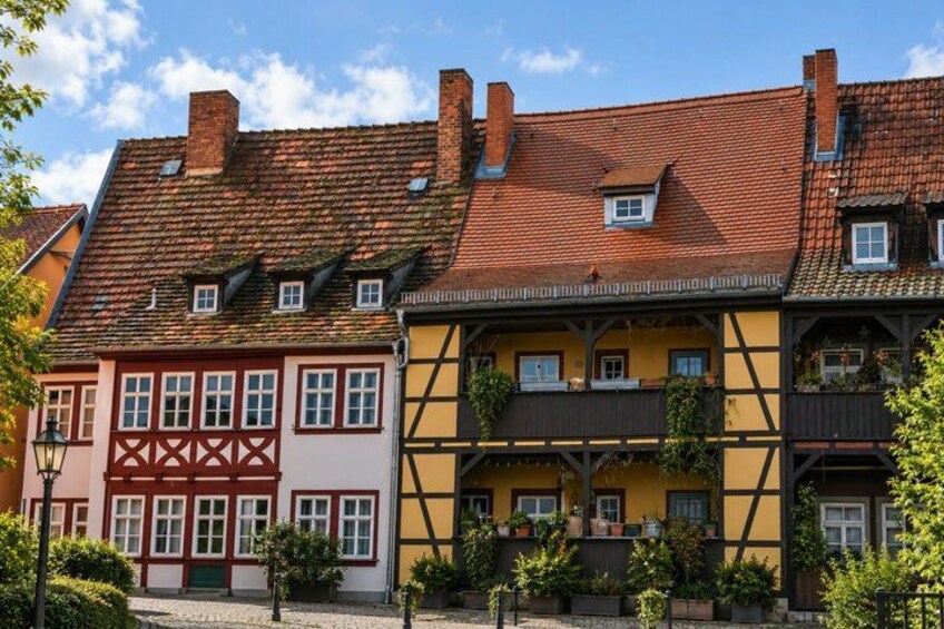A row of traditional half-timbered houses with red and yellow facades, under a clear blue sky. 4