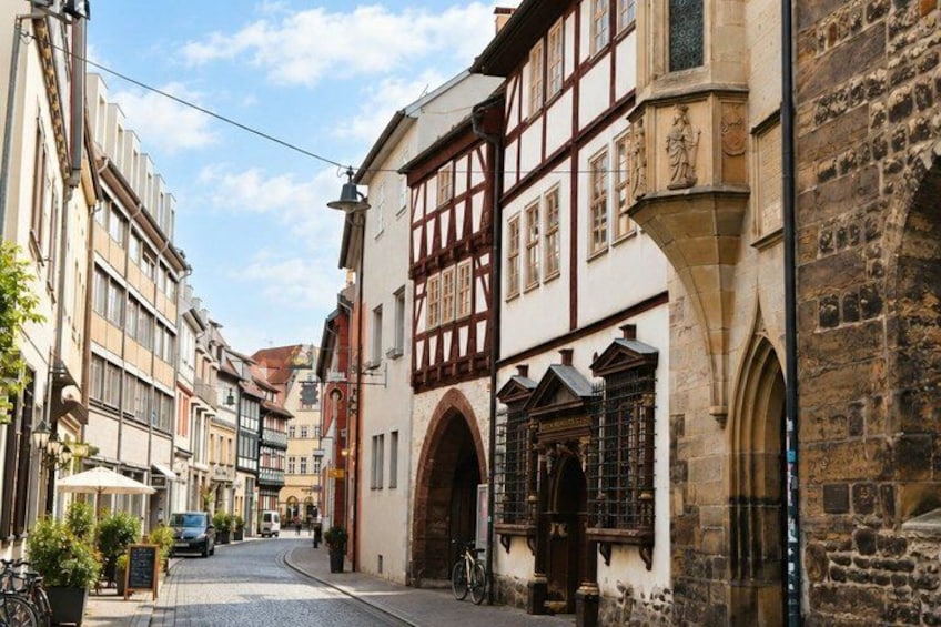 A narrow street lined with historic buildings, including half-timbered houses and stone facades. 2