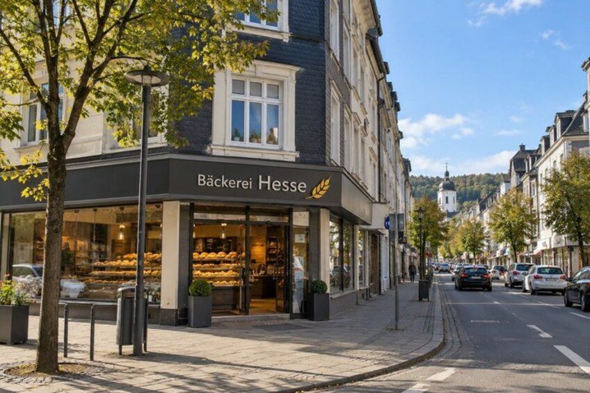 A street with a bakery named 'Bäckerei Hesse' and parked cars. 3