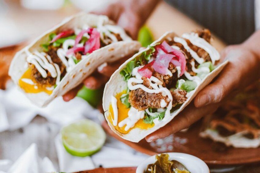 Two tacos with meat, lettuce, and sauce. 1