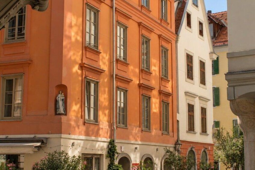 A building with a statue, arched windows, and a white facade. 2
