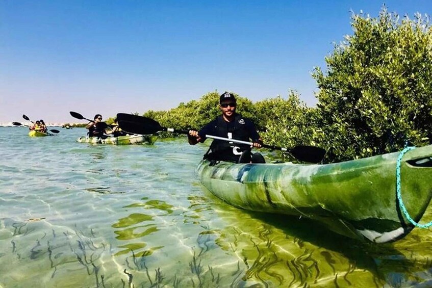 Personas haciendo kayak en aguas claras y poco profundas, con vegetación a los lados. 3