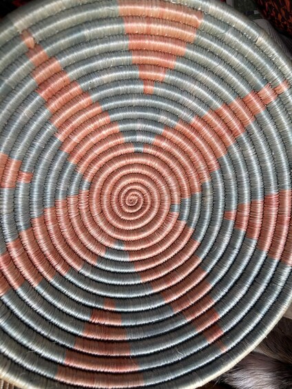 Una cesta circular tejida con anillos concéntricos en tonos grises y rojos. 3