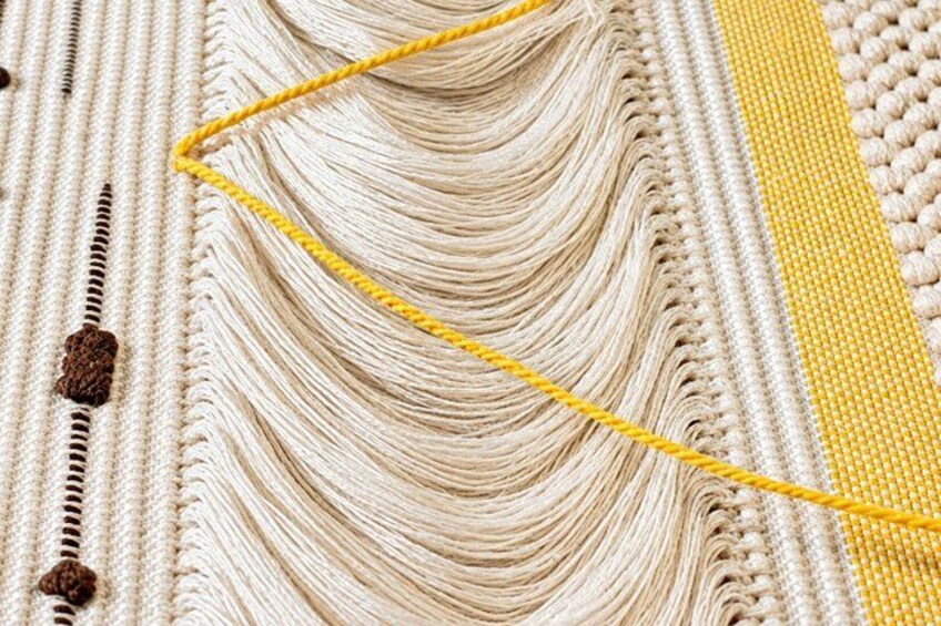 A close-up of a woven textile with a yellow thread. 3