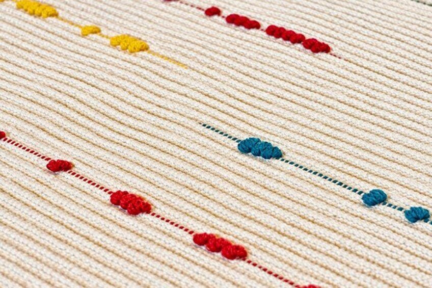 A close-up of a textured fabric with a striped pattern and decorative elements. 5