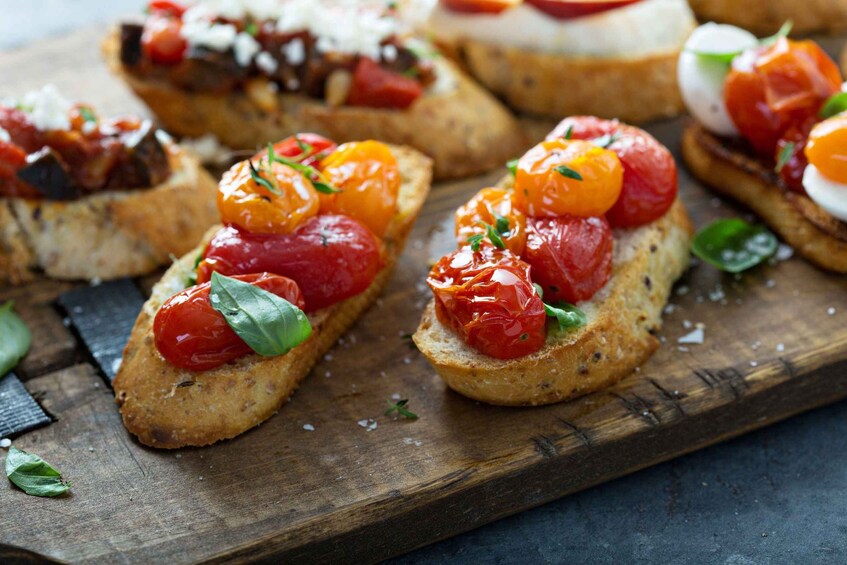 Une planche en bois sur laquelle sont disposées plusieurs tranches de bruschetta garnies de tomates et de basilic. 4