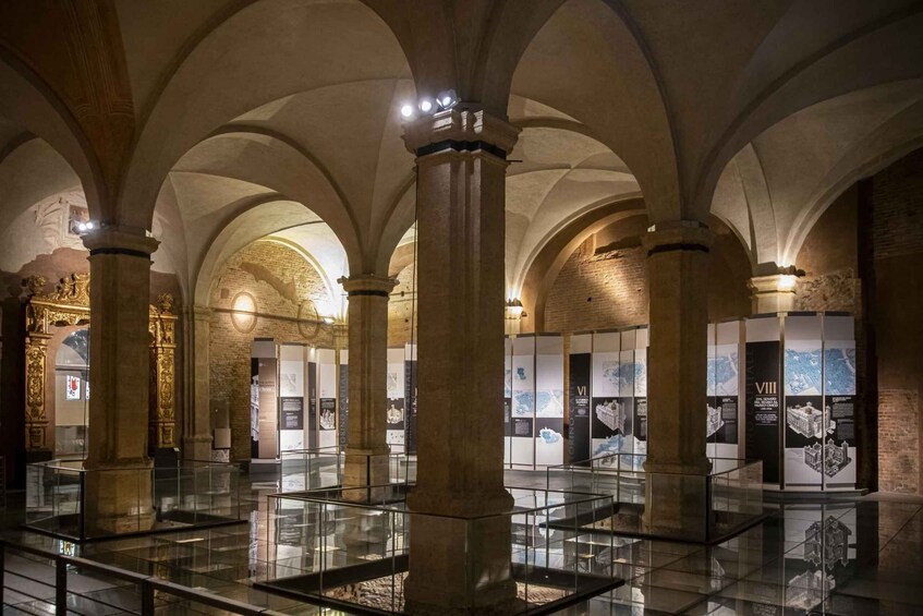 Un interior con techos abovedados y columnas, que exhibe exposiciones históricas y paneles informativos. 2