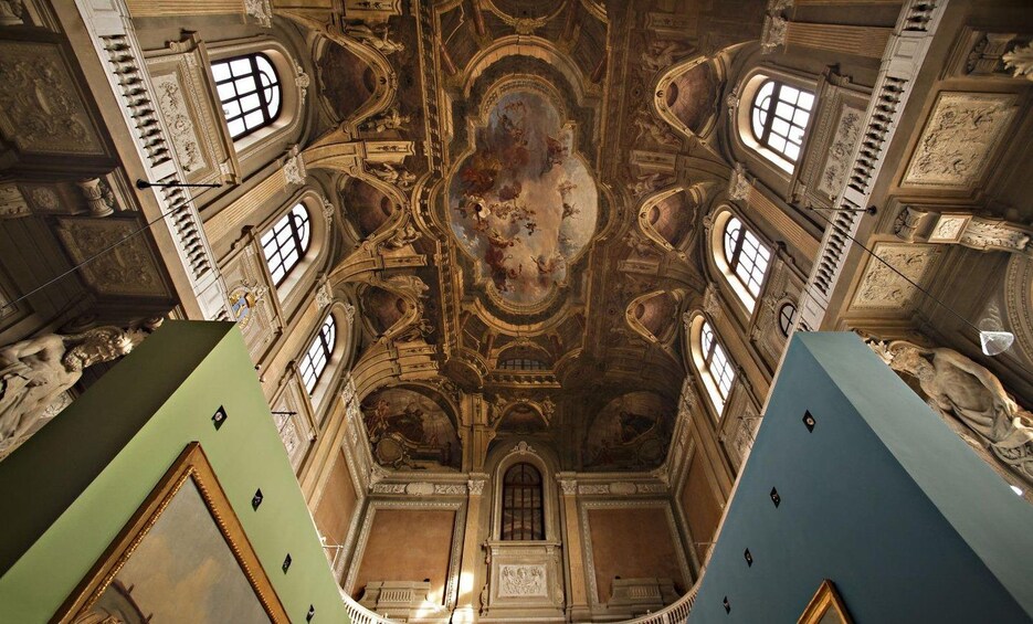 Un interior ornamentado con techo alto, ventanas arqueadas y detallados frescos. 3