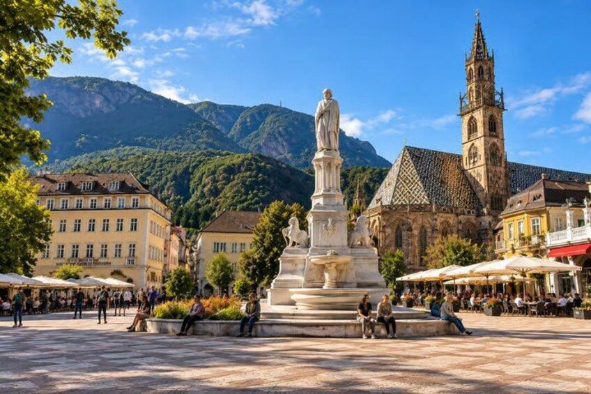 A square with a statue, buildings, and a church with a tower. 1