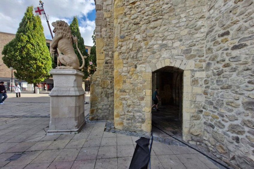 A stone building with a lion statue, a tree, and a flag. 2