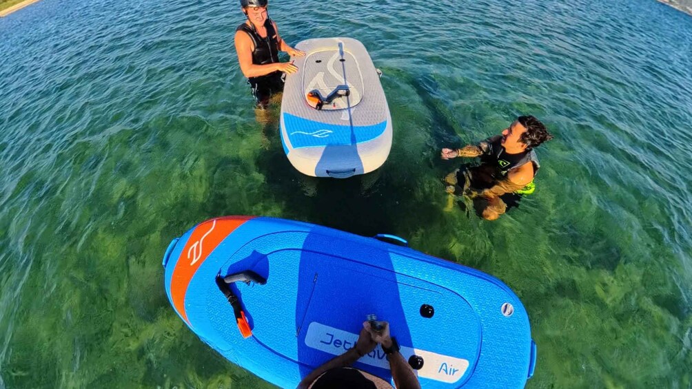 Three people in a body of water with surfboards. 2