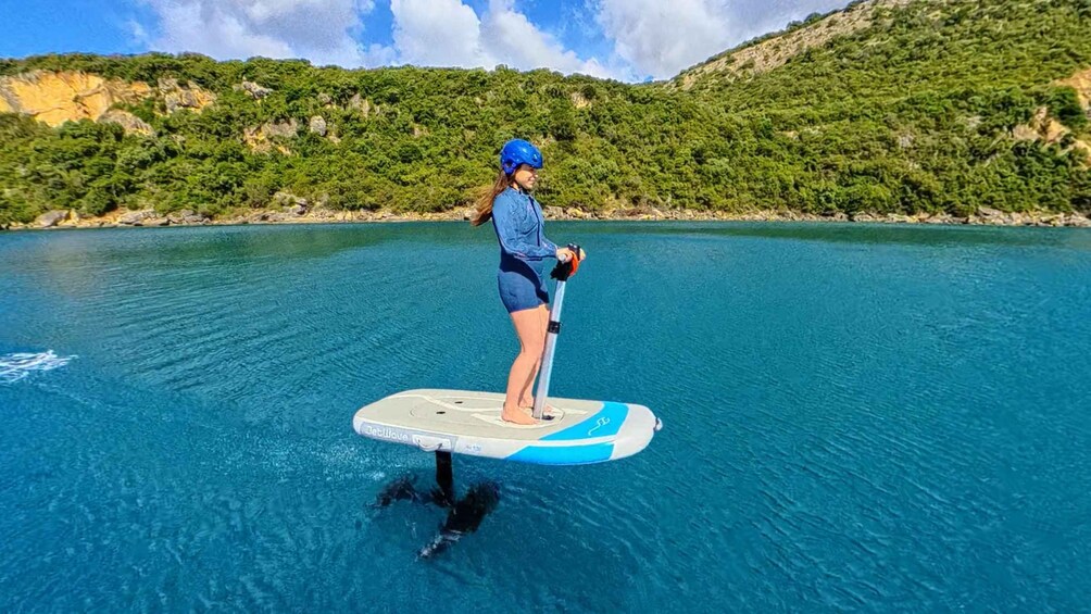 A person paddleboarding on a calm body of water with a mountainous landscape in the background. 3