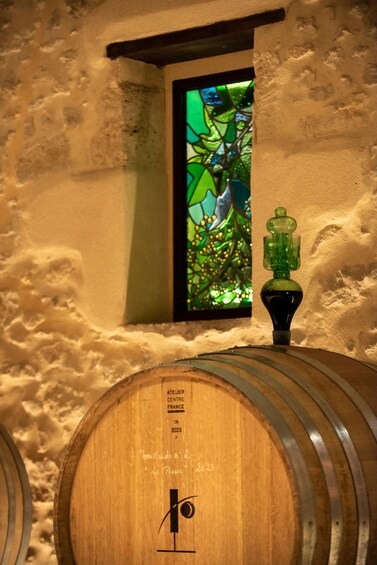 A wooden barrel with a label reading 'ATEUER CENTRE FRANCE 2023' and a small window with a stained glass design. 5