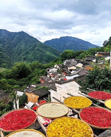 Un village de montagne aux bâtiments traditionnels, où l’on peut admirer une variété de plantes séchées aux couleurs vives, exposées dans des paniers. 2