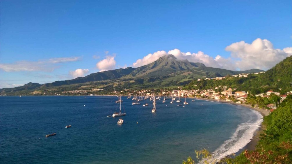 Une ville côtière avec une montagne en arrière-plan, des bateaux sur l’eau et une plage. 1