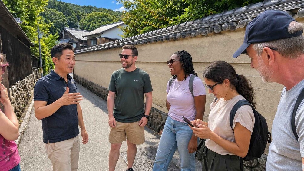 A group of people standing on a stone pathway with traditional Japanese architecture in the background. 3