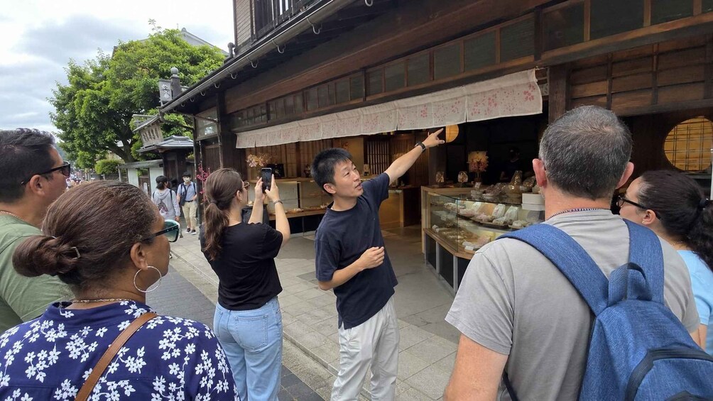 A group of people standing outside a traditional building with a signboard. 2