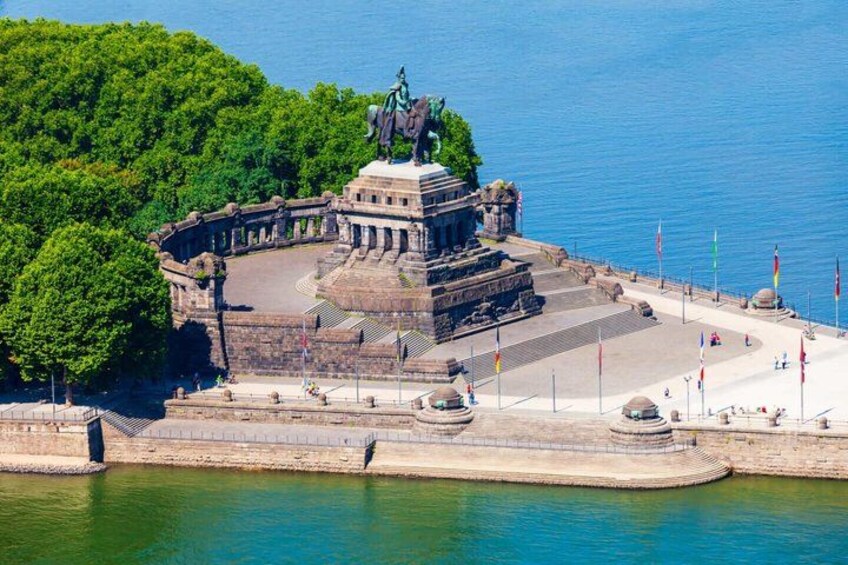 A historical monument surrounded by water, with flags and a paved area in the foreground. 4