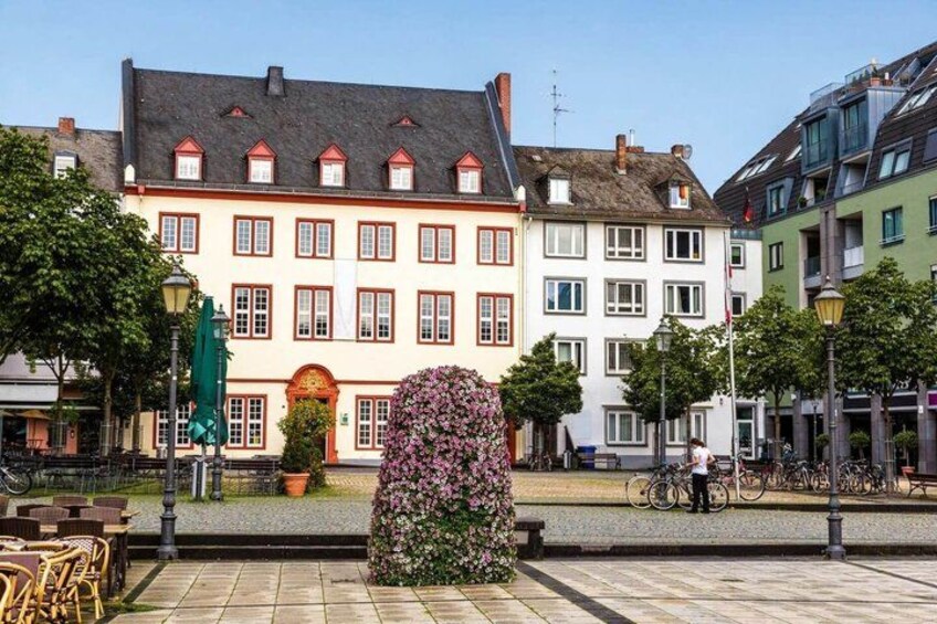 A European-style building with a red and white facade, a cobblestone plaza, and a flower-covered column. 3