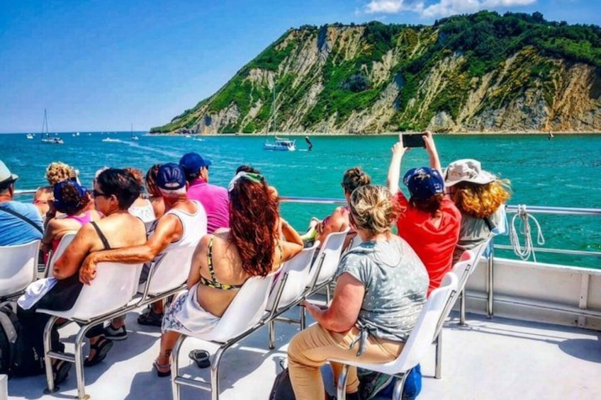 People on a boat, a coastal landscape with cliffs, and the sea. 1