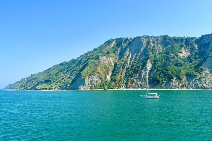 A boat on calm turquoise waters with a mountainous coastline in the background. 4