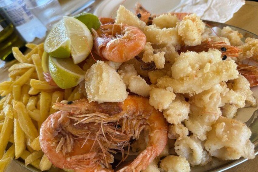 A plate of food with shrimp, cauliflower, and fries. 3