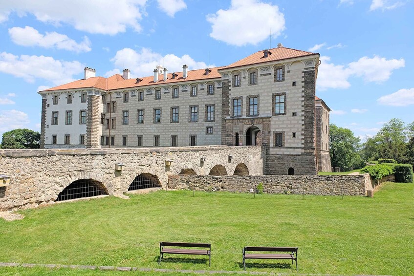 A large historic building with a stone facade, arched windows, and a red-tiled roof. 1