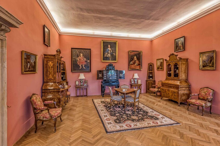 A room with pink walls, wooden furniture, and various framed artworks. 3