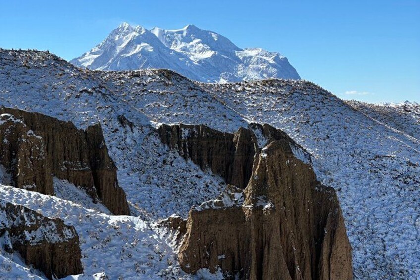 A snow-covered mountain with rocky cliffs and a clear blue sky. 4