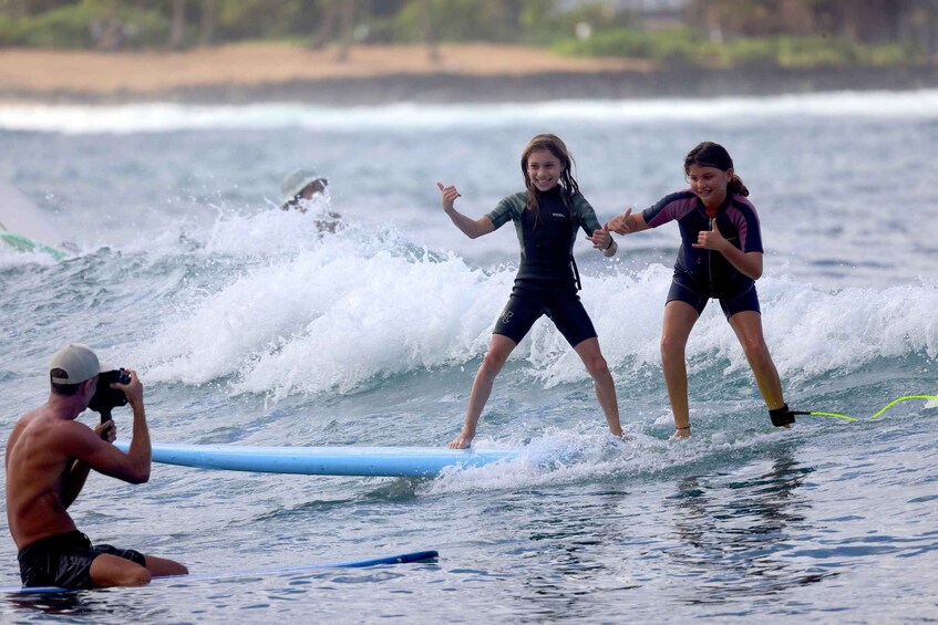 Two people surfing on a wave with a photographer capturing the moment. 5
