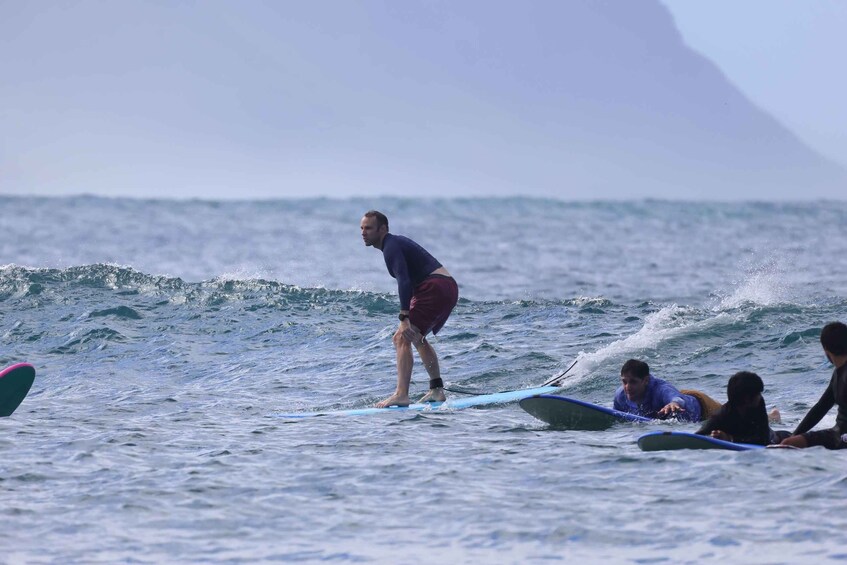 A person surfing on a wave with other surfers in the background. 2