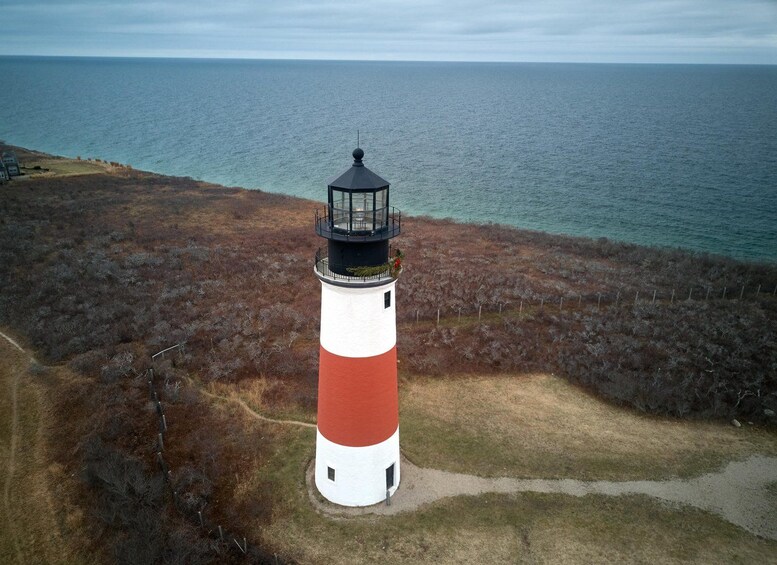 Un faro con una torre a rayas rojas y blancas, rodeado por un paisaje costero. 4