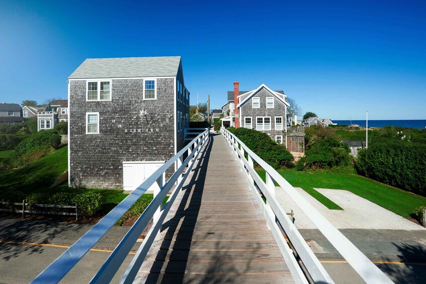 Un paseo marítimo de madera que conduce a una zona costera con casas y un faro. 5