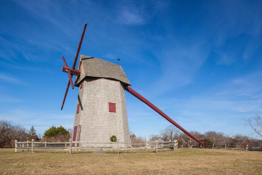 Un molino de viento con travesaño rojo y torre de madera. 3