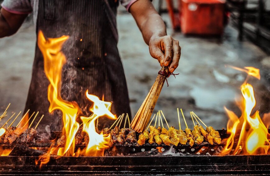 Una persona asando brochetas sobre fuego abierto. 1