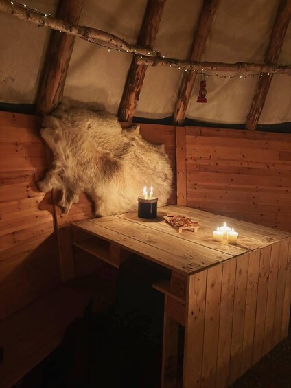 A rustic wooden interior with a fur-covered wall, a wooden table with candles, and a string of lights. 5