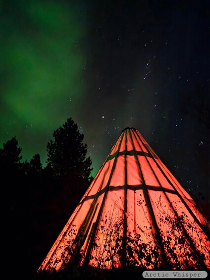 A conical structure illuminated with red lights against a night sky with visible stars. 1